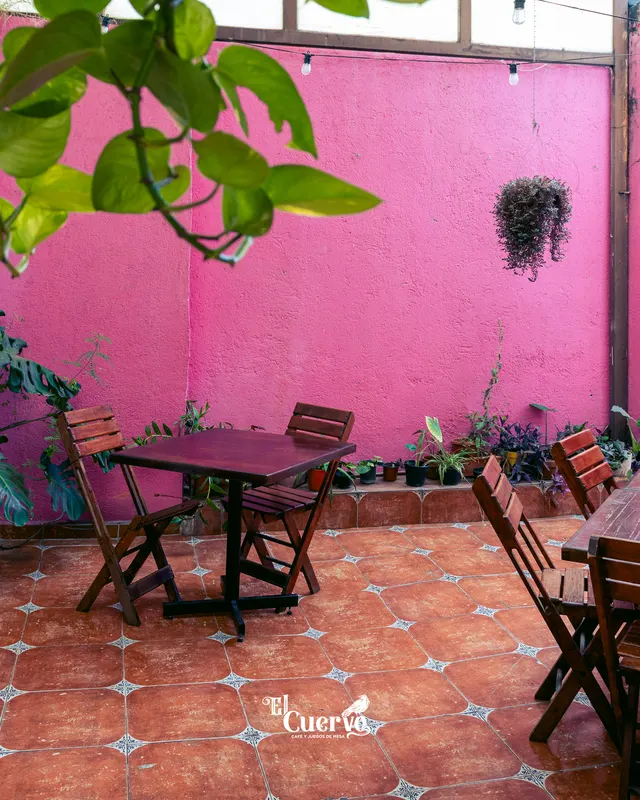 El patio rosa de El Cuervo, con mesas de madera y piso de barro